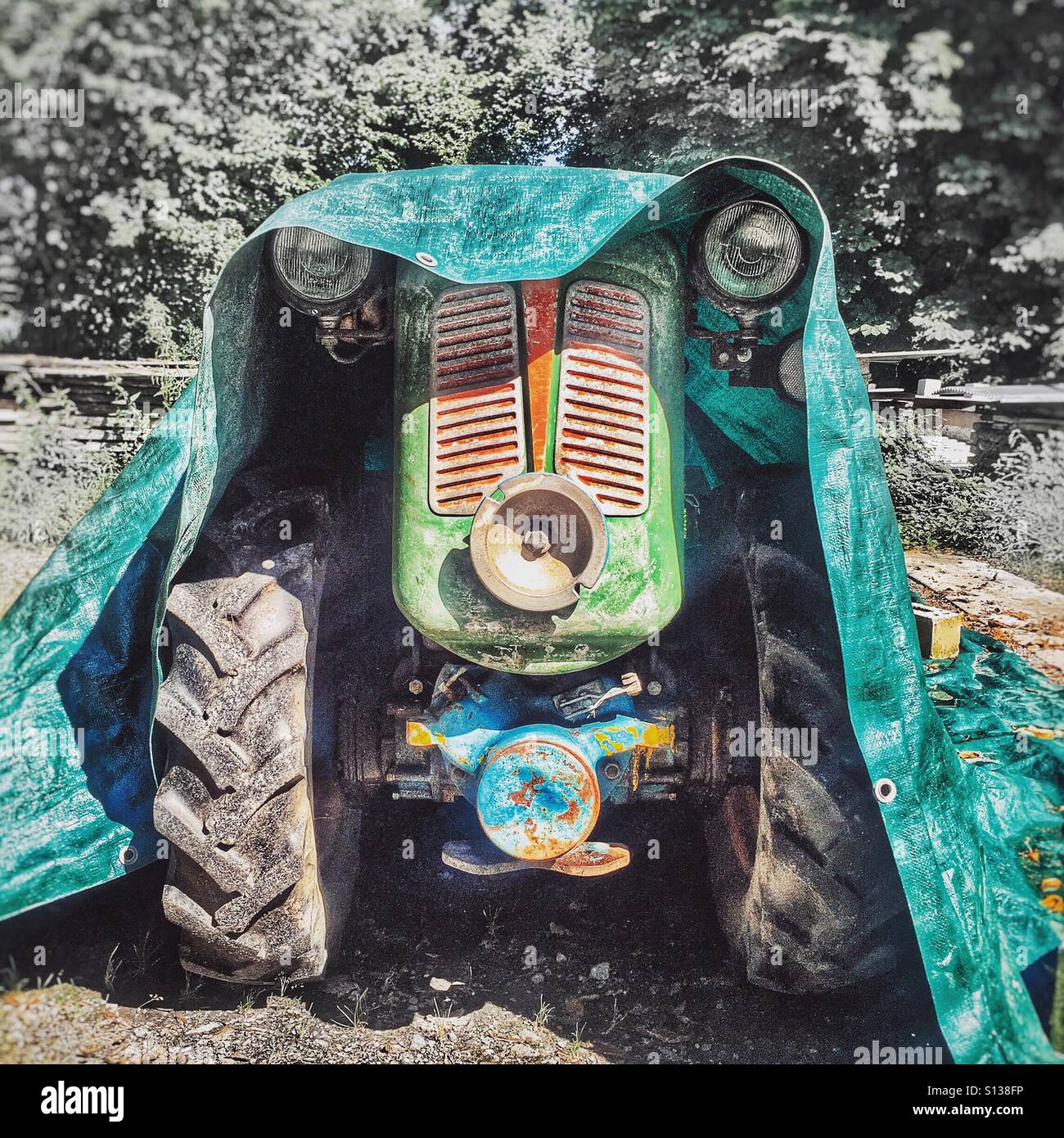 Characterful old tractor peering out from under a tarpaulin - Smartphone Captured Stock Image