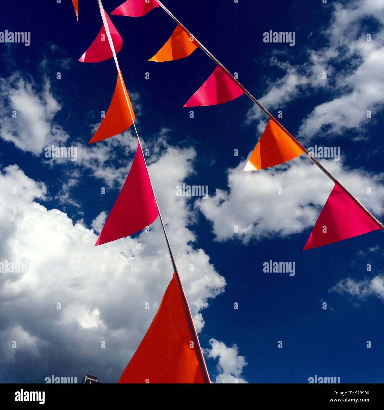 Colorful flags in front of a blue sky with clouds. Stock Photo