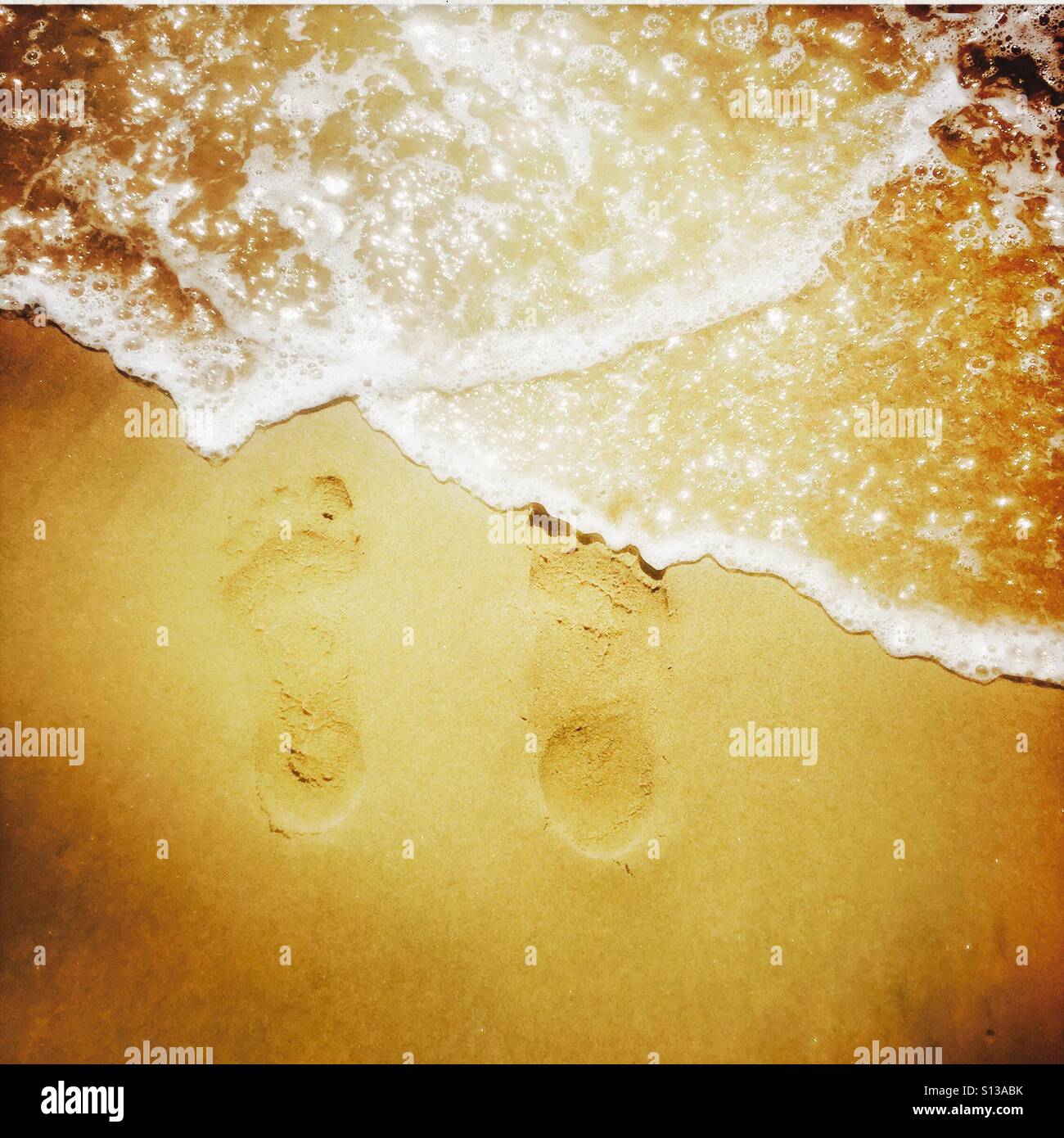 Water washing over footprints in the sand. Manhattan Beach, California USA. - Smartphone Captured Stock Image