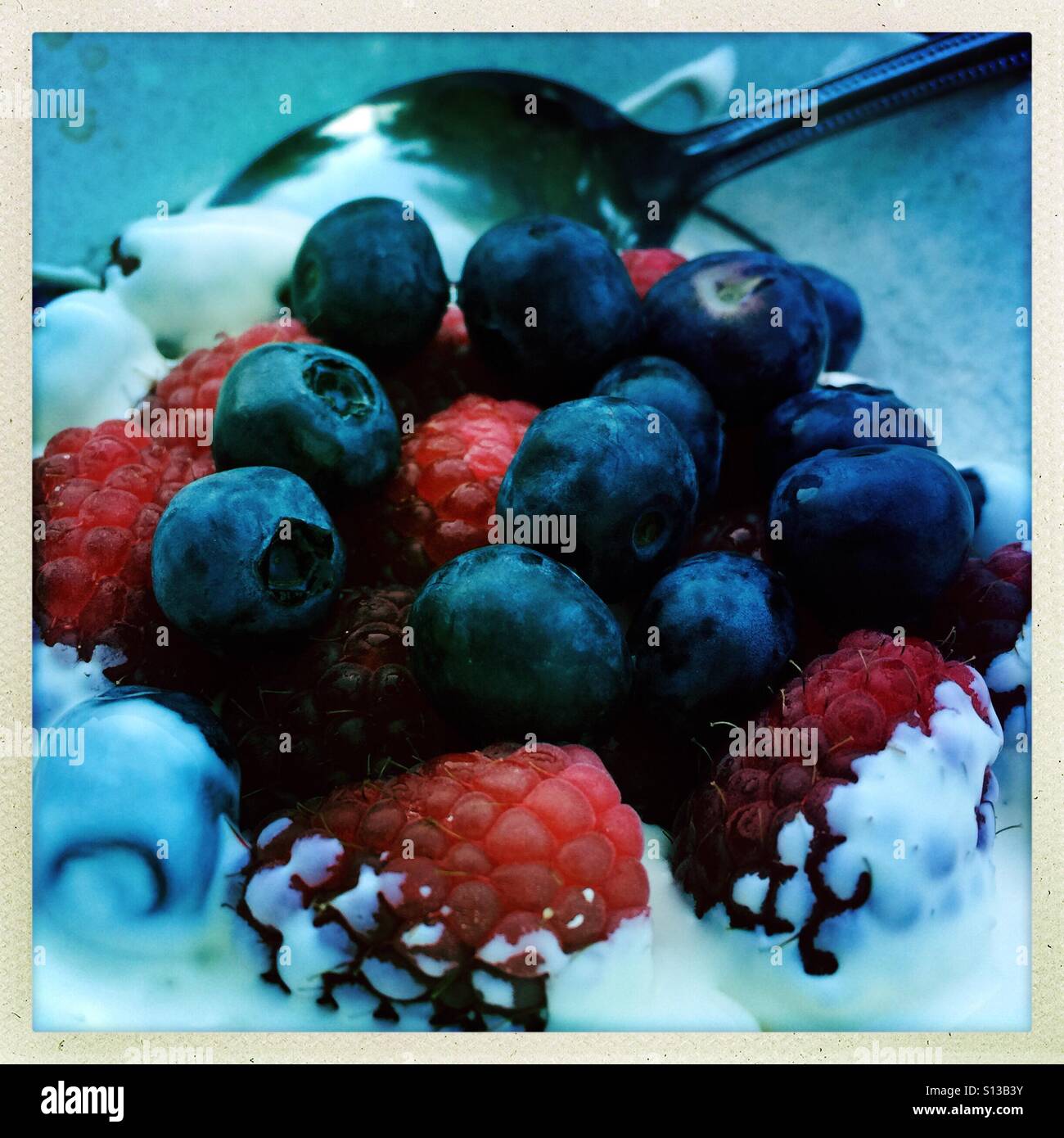 Bowl of raspberries, blueberries and cream Stock Photo
