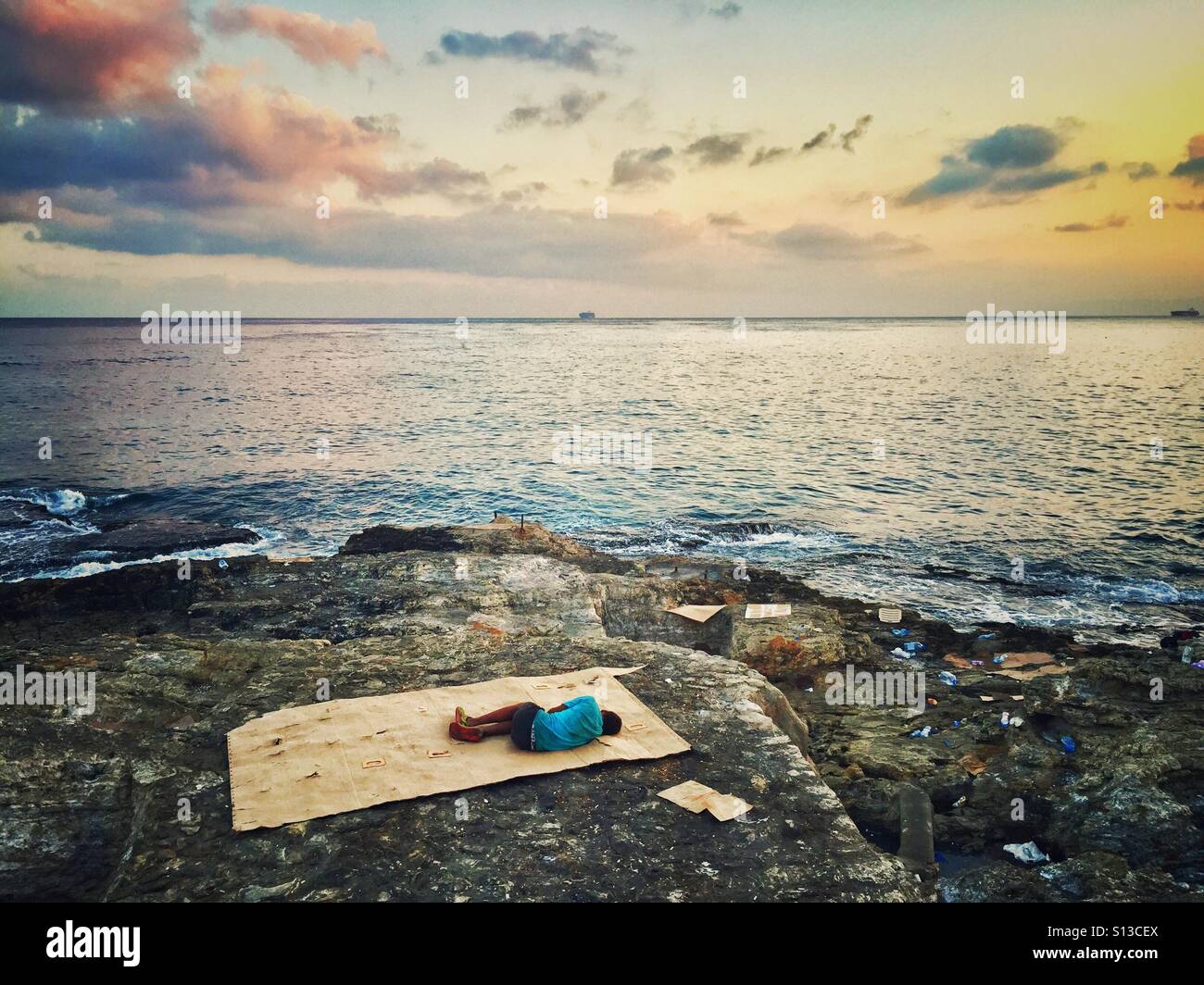 Syrian refugee child sleeping on the seashore Beirut Lebanon - Smartphone Captured Stock Image