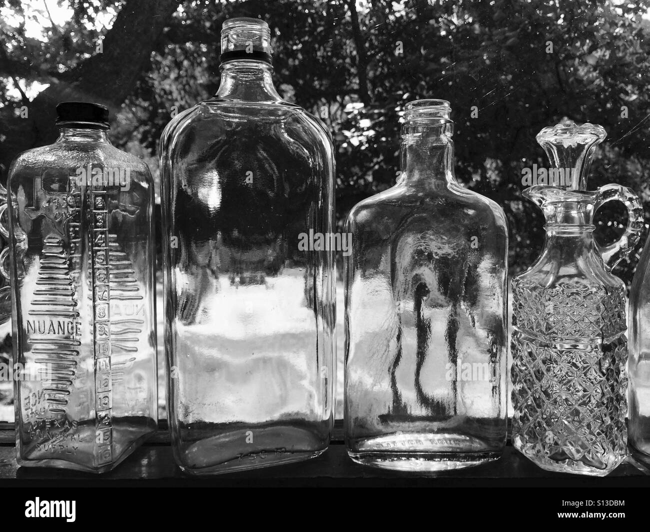 Antique glassware bottles sit upon a windowsill. Stock Photo