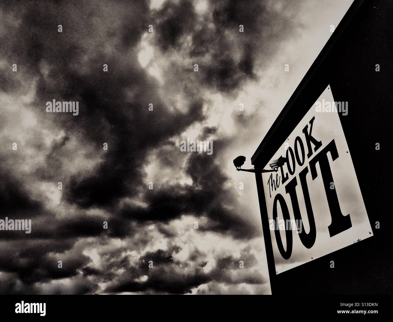 Look Out sign and security camera against dramatic sky Stock Photo