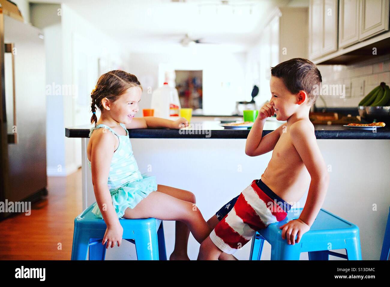 Sibling brother and sister laughing and talking during lunch in the kitchen Stock Photo