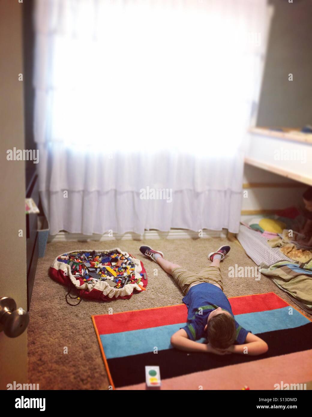 Boy lying on a colorful rug in a bedroom Stock Photo