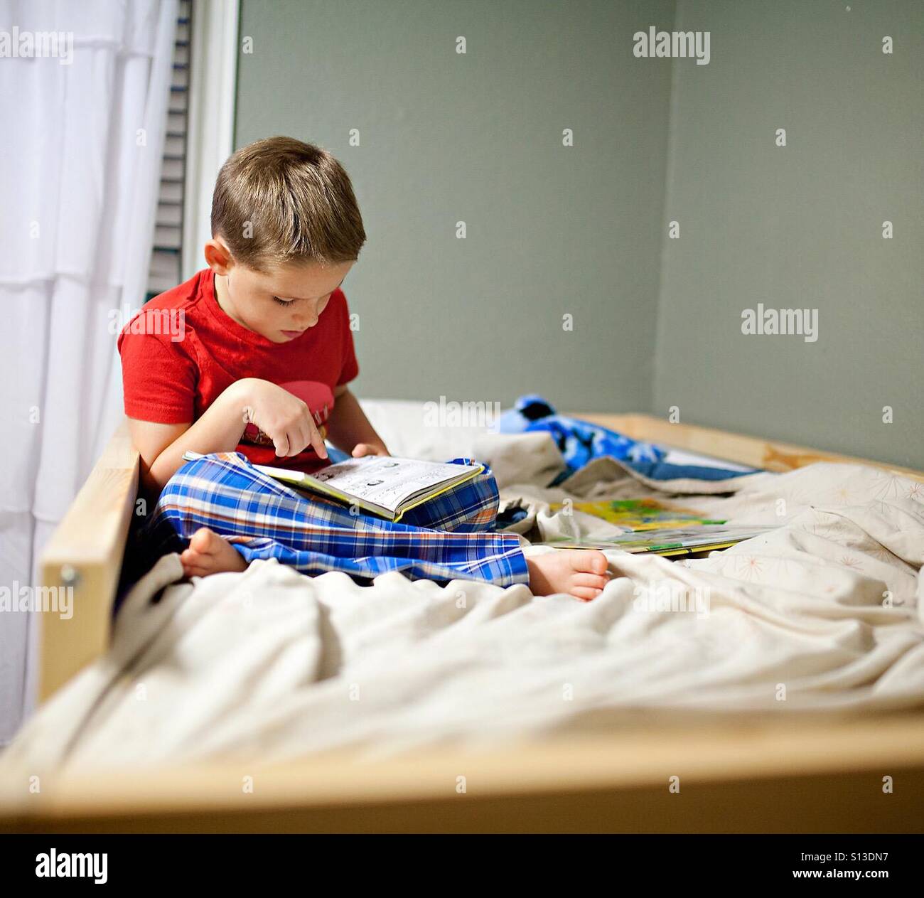 Boy reading a book in bed at home Stock Photo