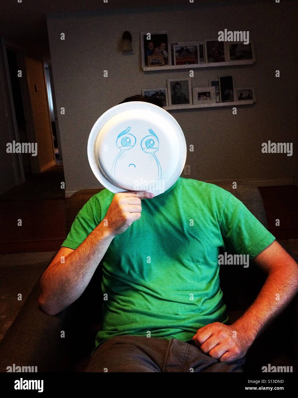 Man holding plate with a sad face drawn on it. Stock Photo
