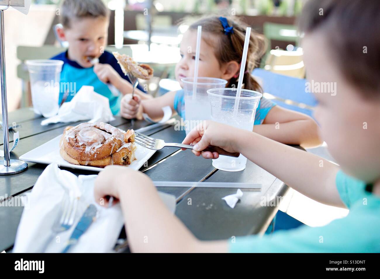 Kids eating a giant cinnamon roll at a restaurant Stock Photo