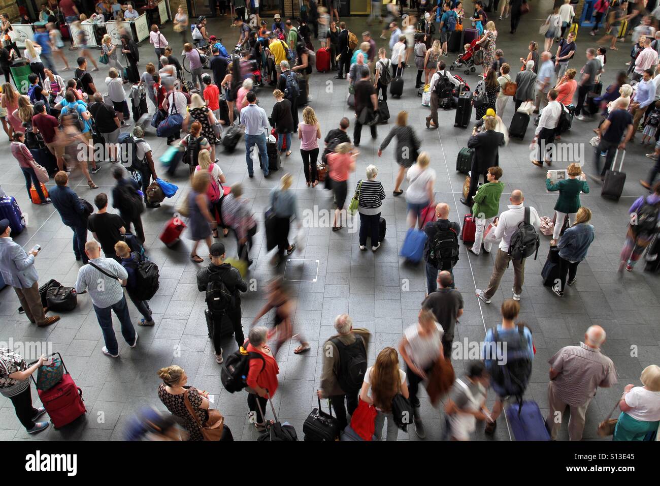 The crowded concourse of London's King's Cross train station full of passengers, commuters and travelers waiting for information about their trains and platforms. - Smartphone Captured Stock Image