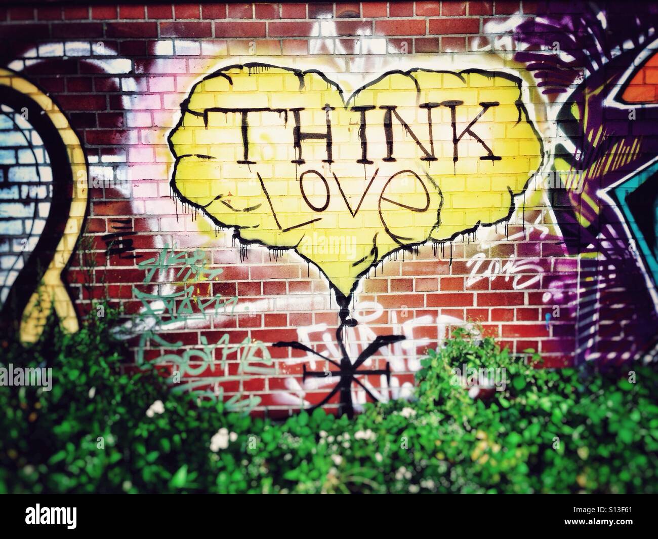 Yellow Think Love Graffiti Heart on a brick Wall in Berlin Kreuzberg - Smartphone Captured Stock Image