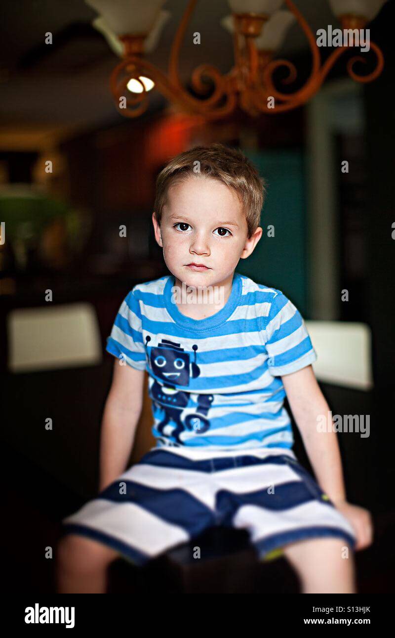 Serious boy in stripes looking sad at camera Stock Photo