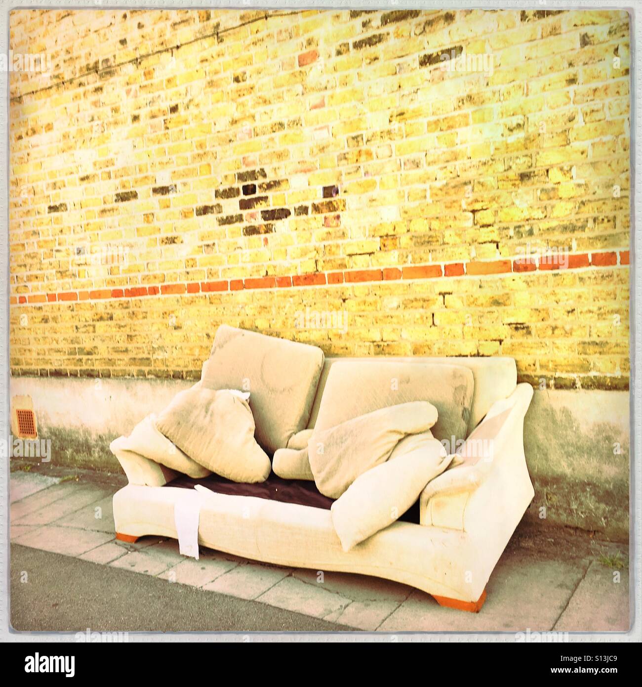Sofa dumped by a wall Stock Photo