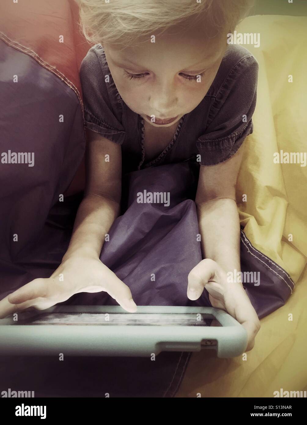 A girl types with her thumbs on her tablet. - Smartphone Captured Stock Image
