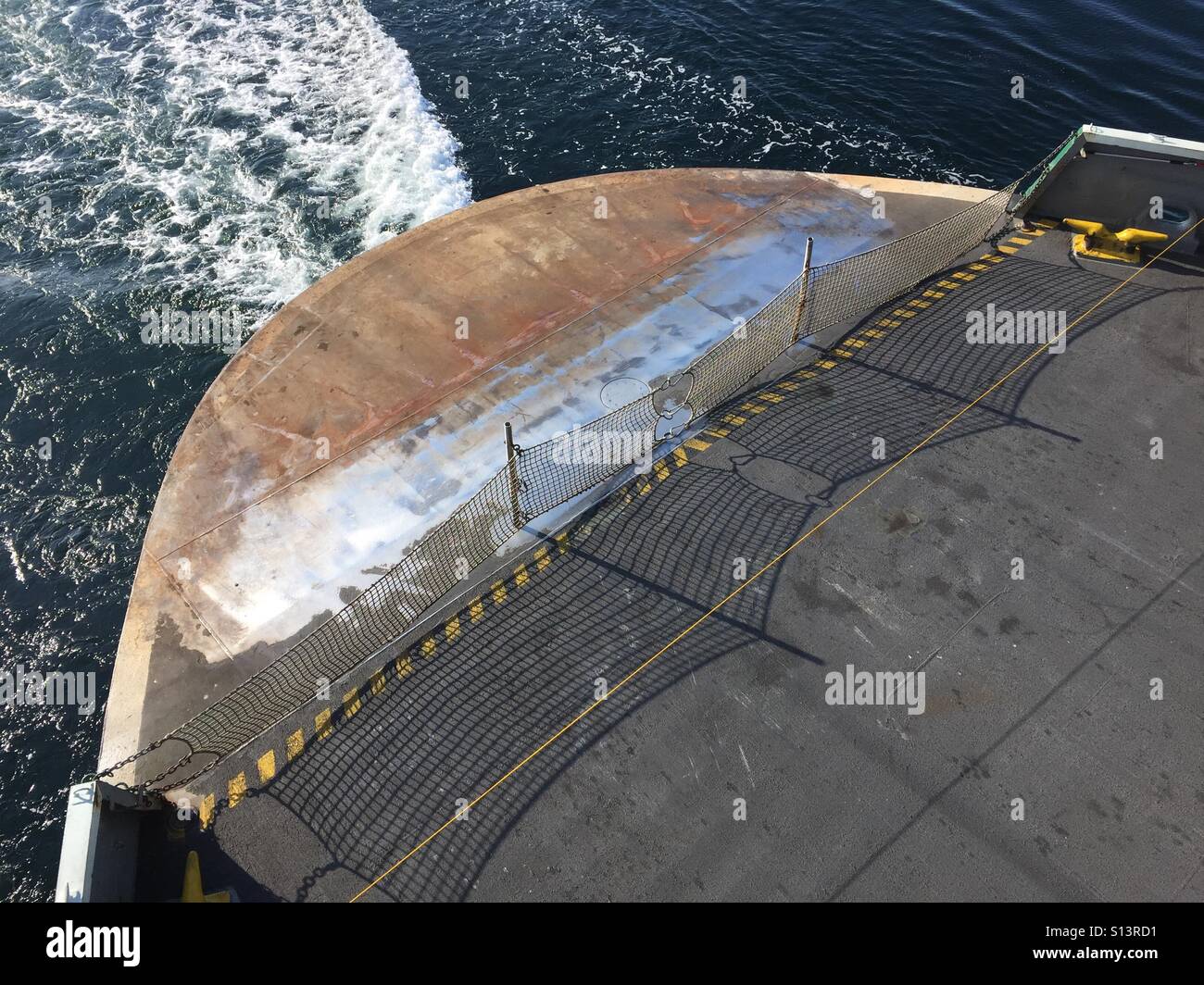 Looking down at the wake from a seattle ferry showing a rusty deck and safety fence - Smartphone Captured Stock Image
