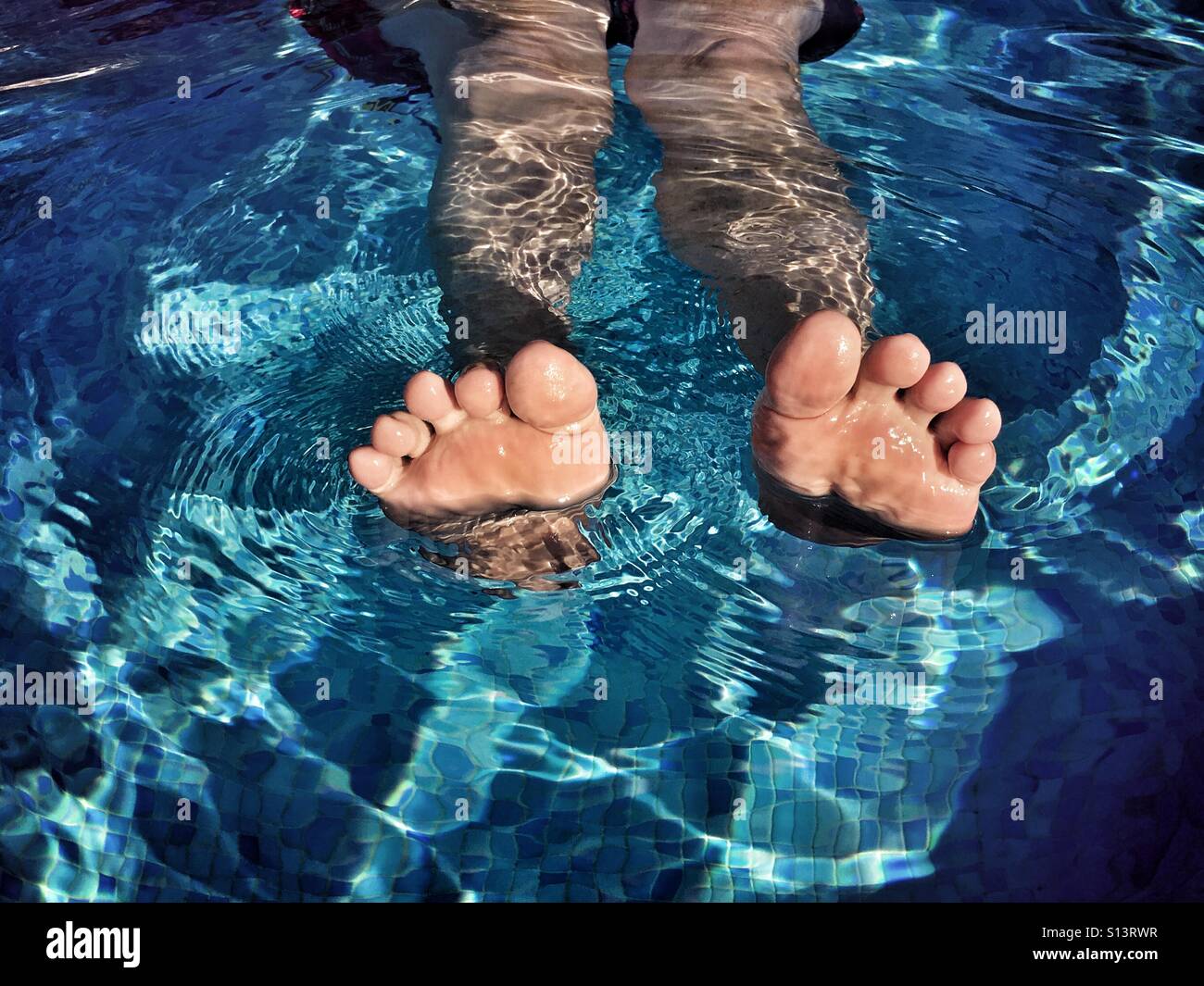 Feet! Woman floating in swimming pool - Smartphone Captured Stock Image