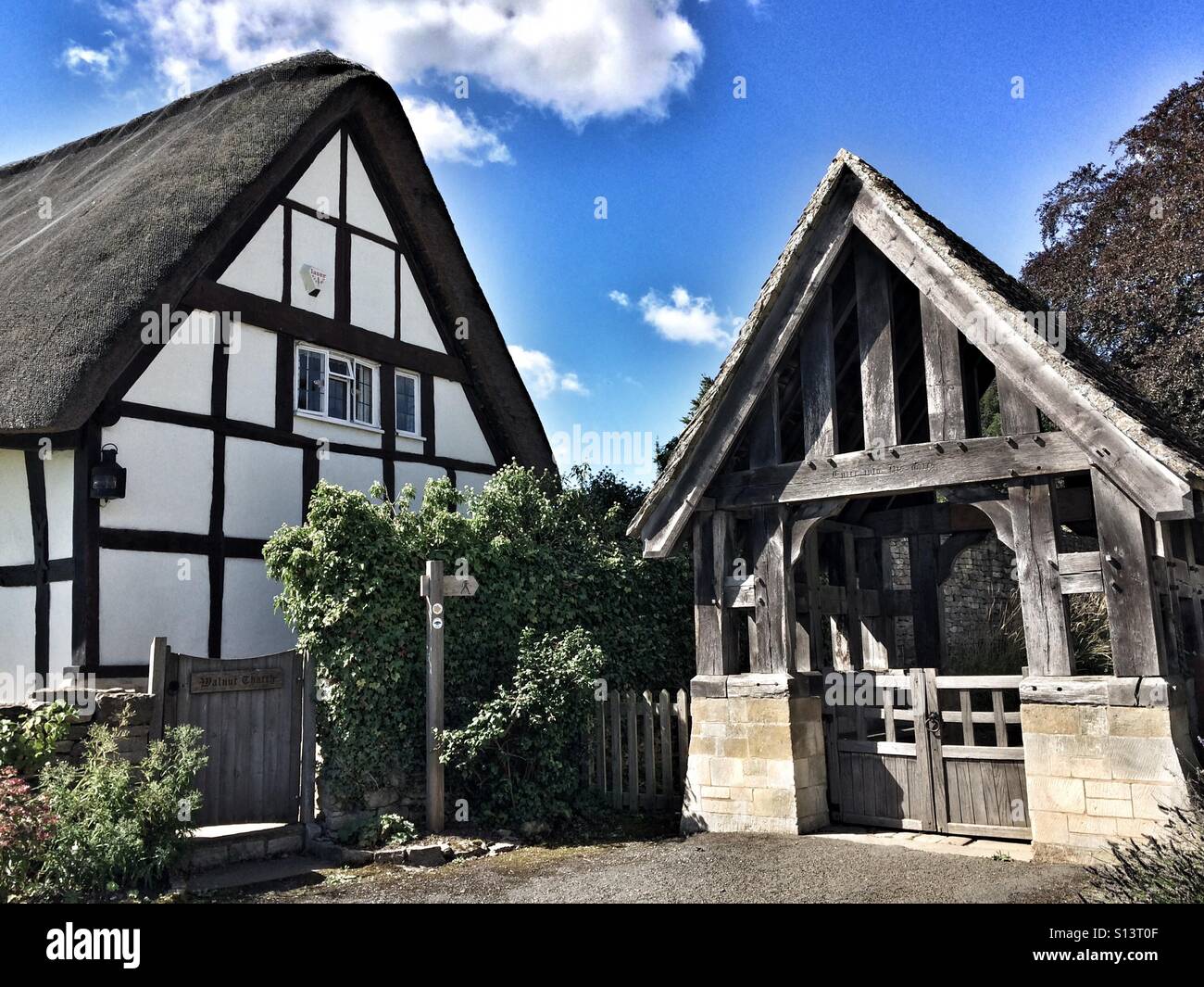 Church gate and thatched cottage in Ashton-under-Hill, Worcestershire Stock Photo