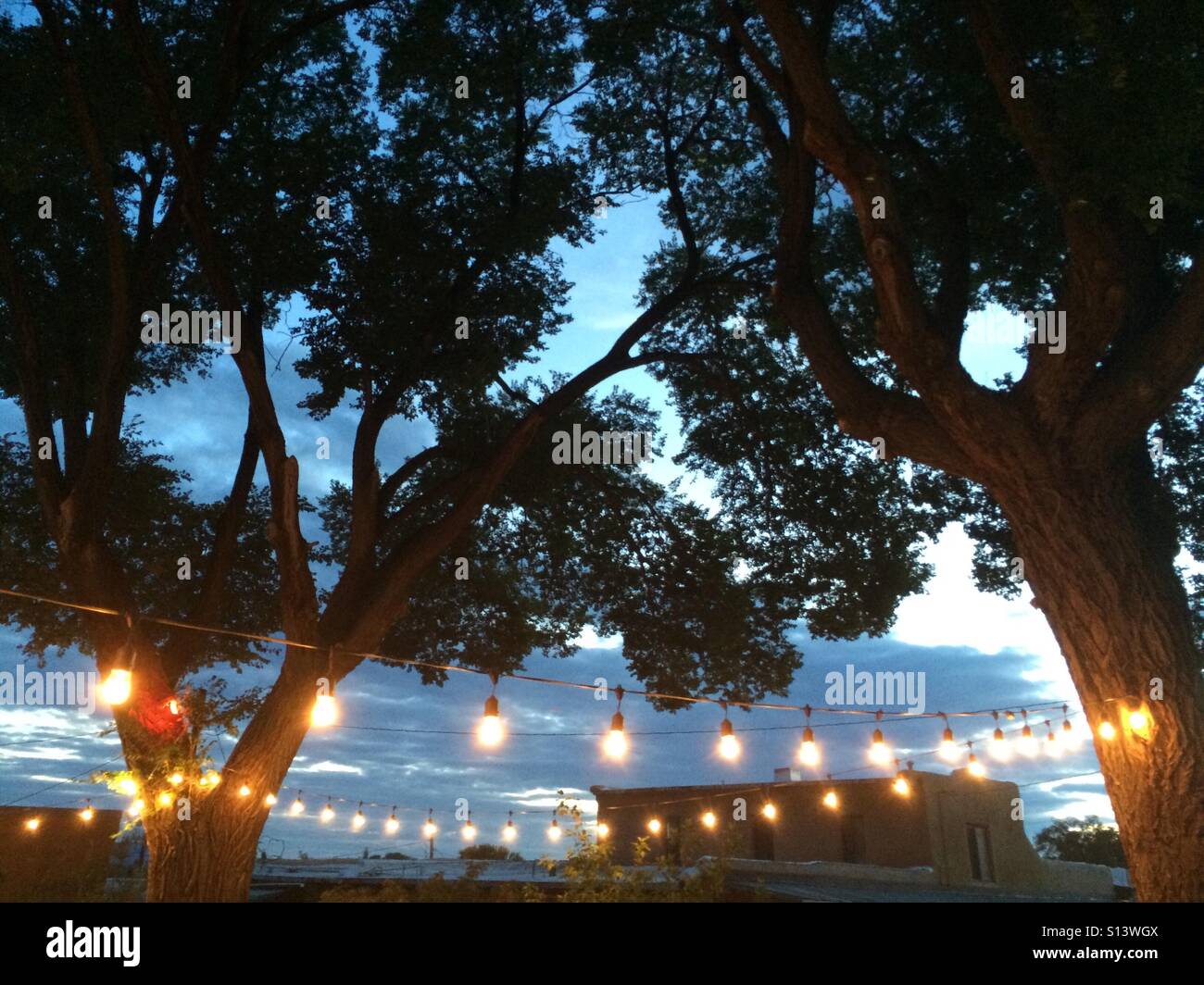 Decorative lights hang in a backyard patio before a evening sky. Stock Photo