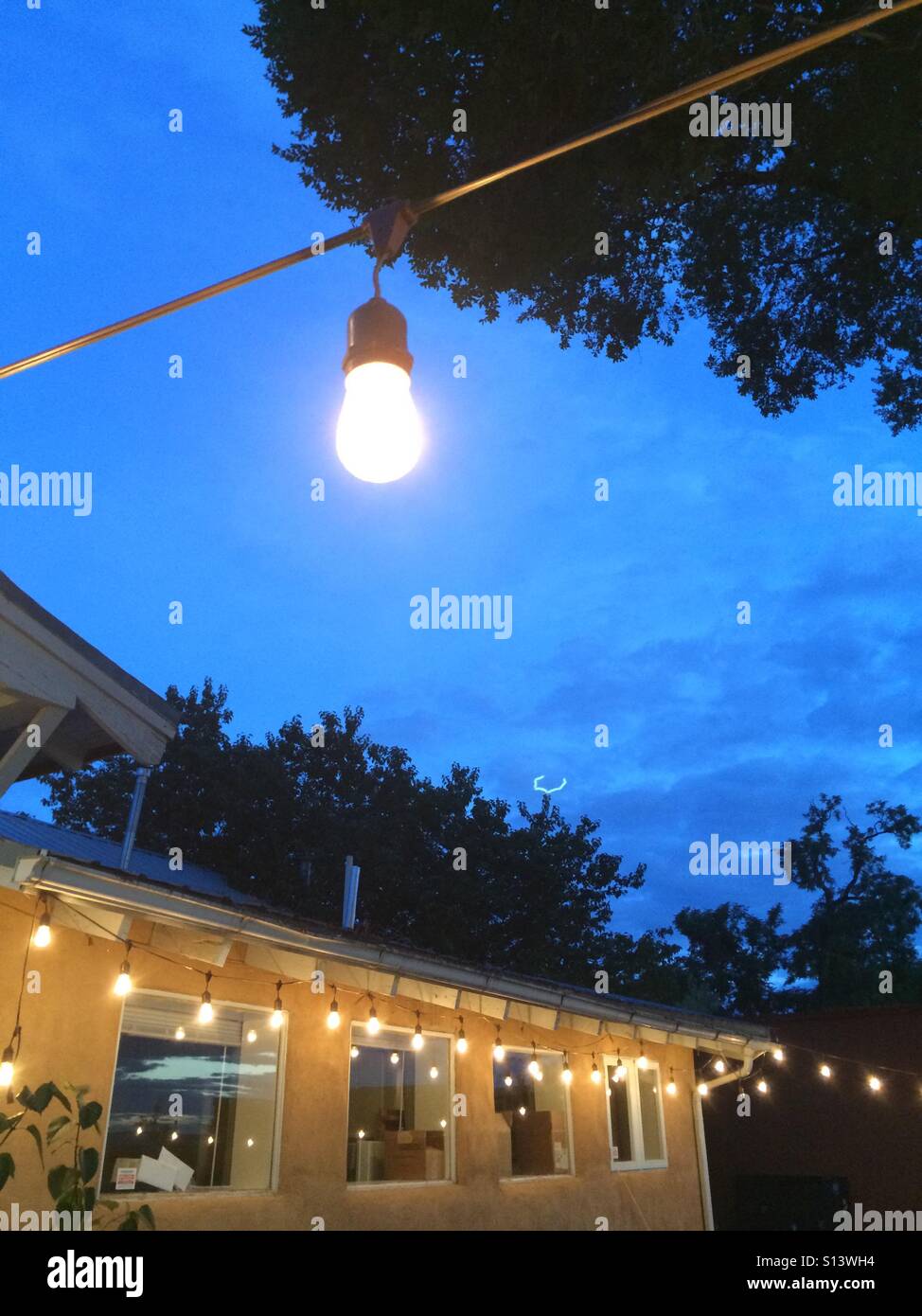 Decorative lights hang in a backyard space. Stock Photo
