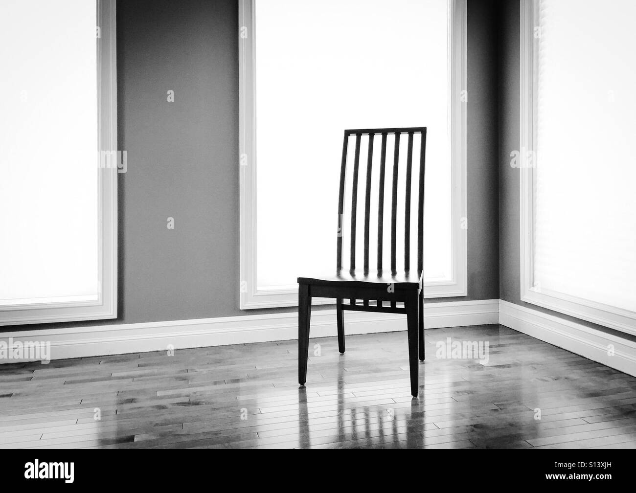 A slat-back chair stands alone in a room. - Smartphone Captured Stock Image