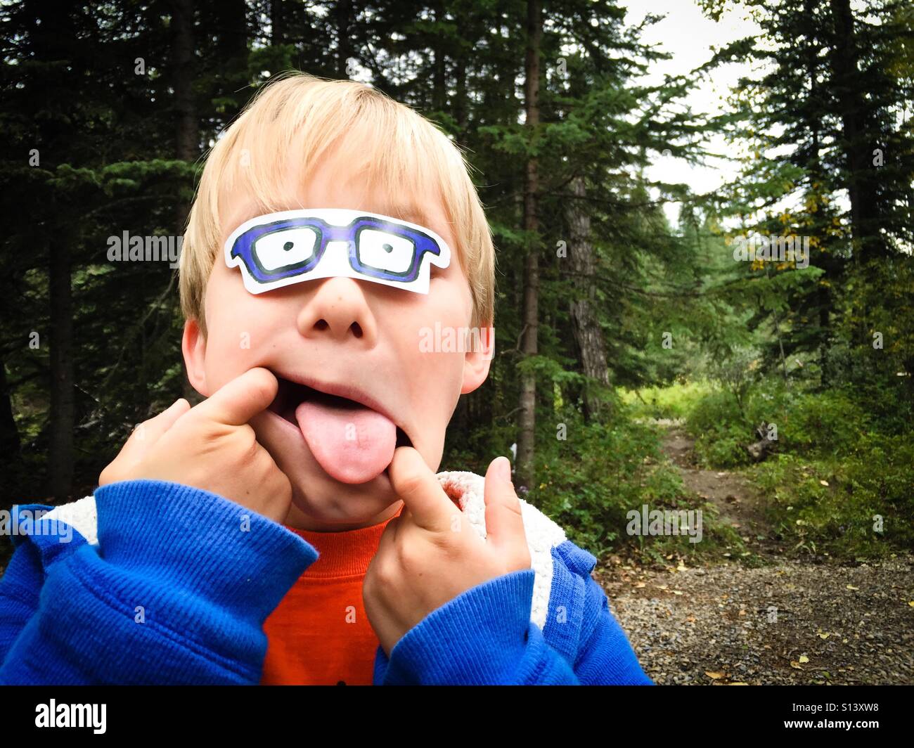 A boy playing outdoors makes a funny face. Stock Photo
