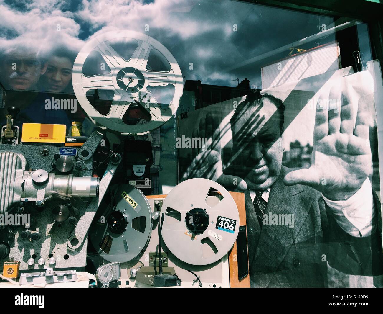 Vintage movie film projectors and cinema poster showing Alfred Hitchcock on a east London shop's window display. - Smartphone Captured Stock Image