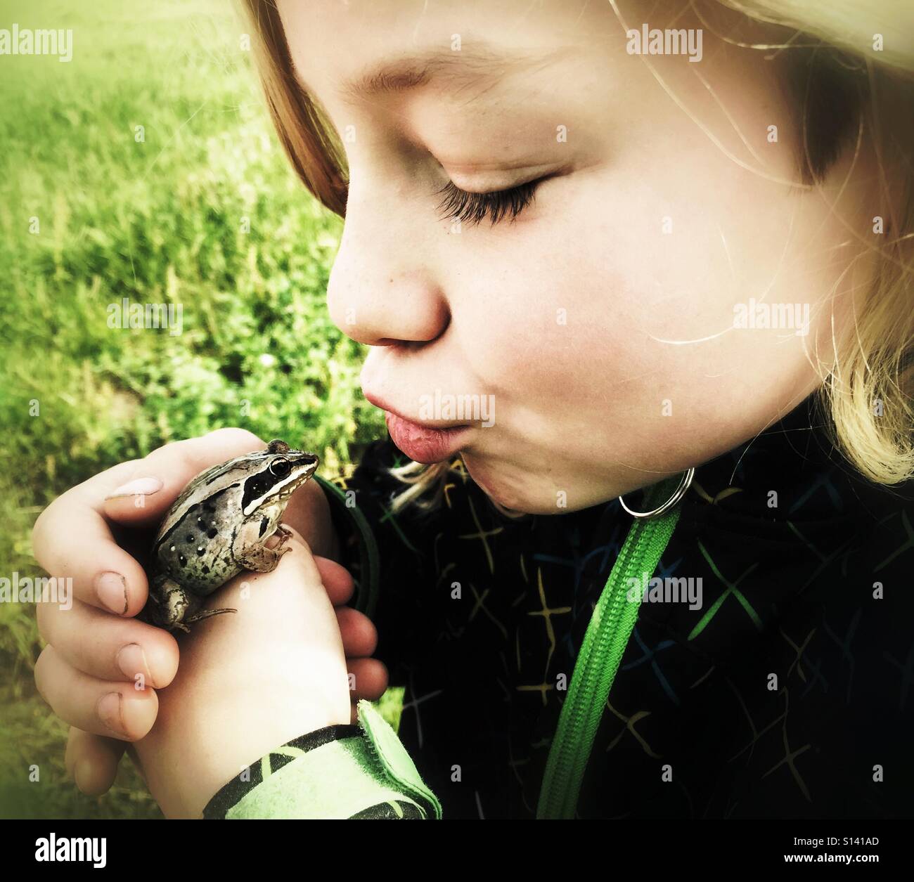 A girl purses her lips to kiss a frog Stock Photo - Alamy