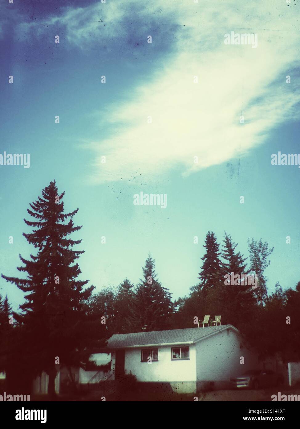 A house with two chairs balanced on the roof Stock Photo Alamy