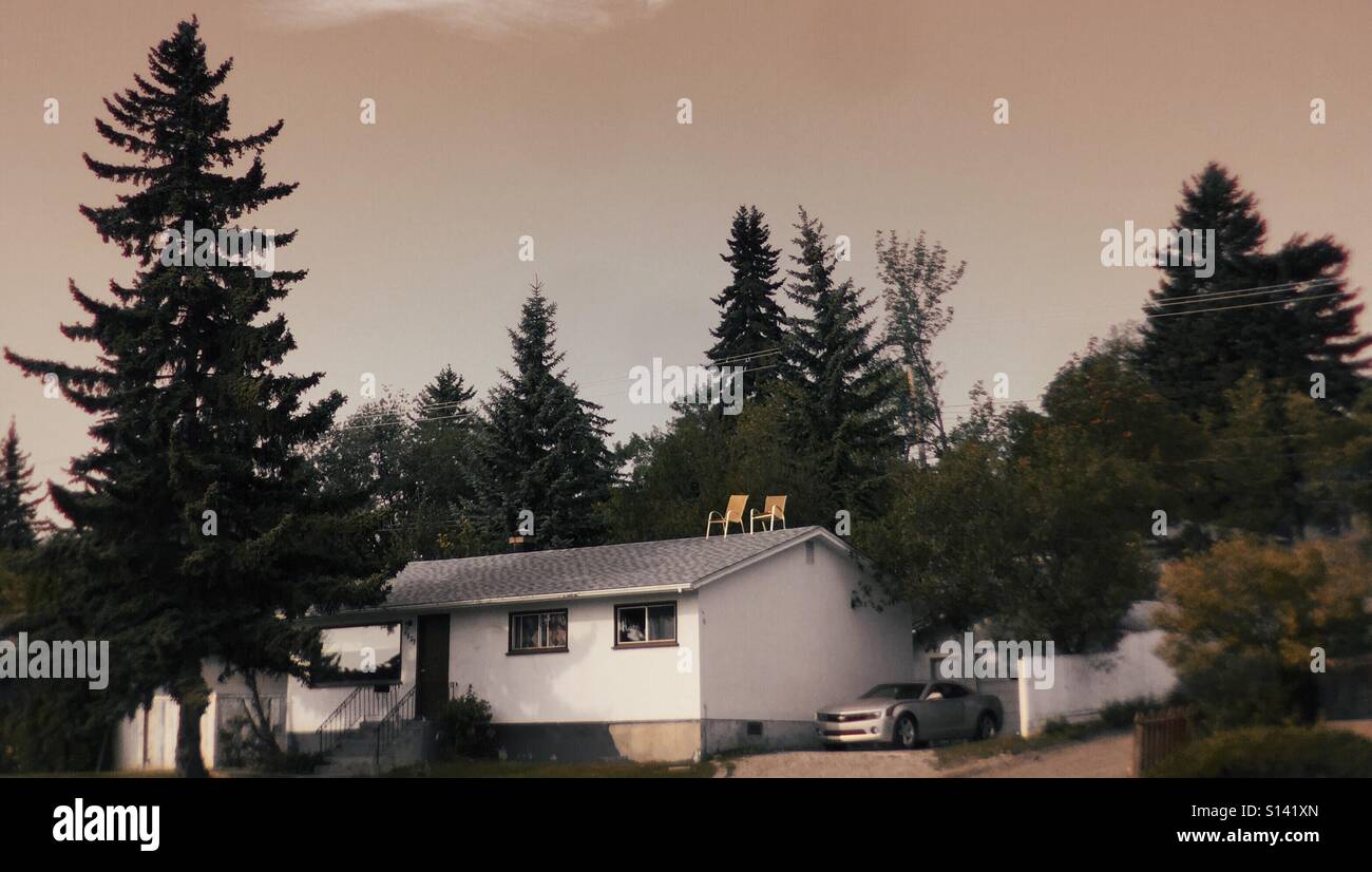 A house with two chairs balanced on the roof Stock Photo Alamy