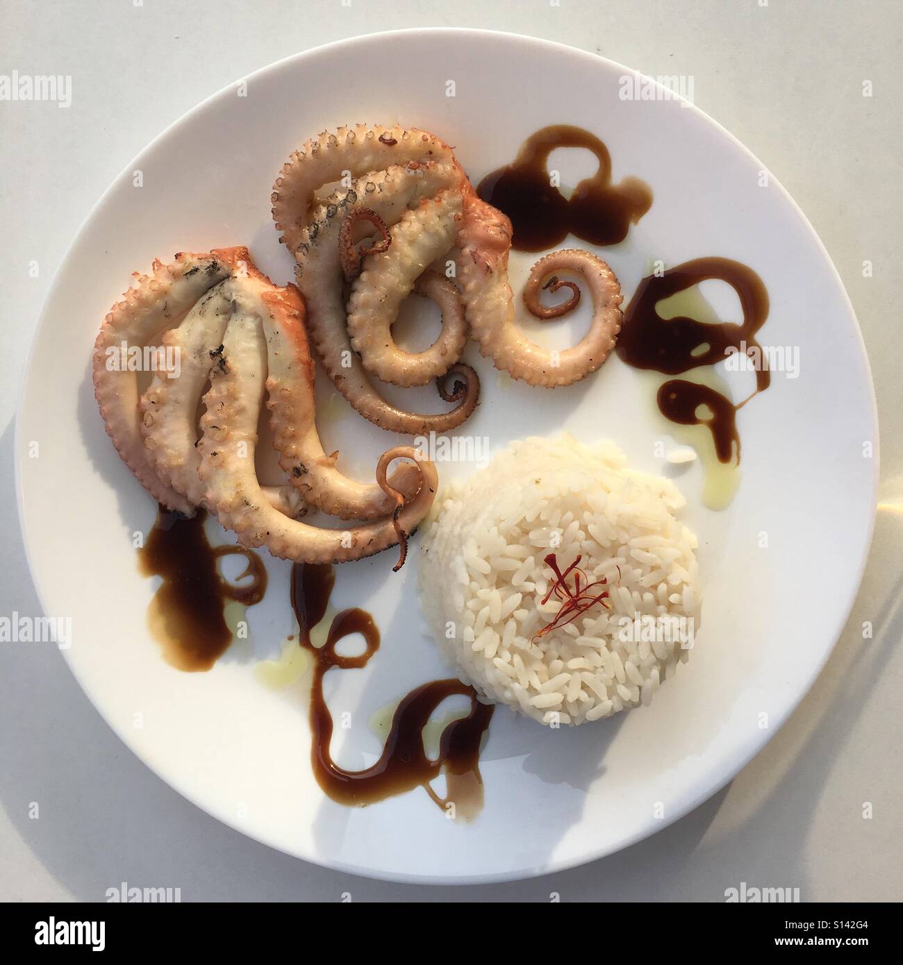 Grilled octopus with a side of rice topped with Saffron Stock Photo