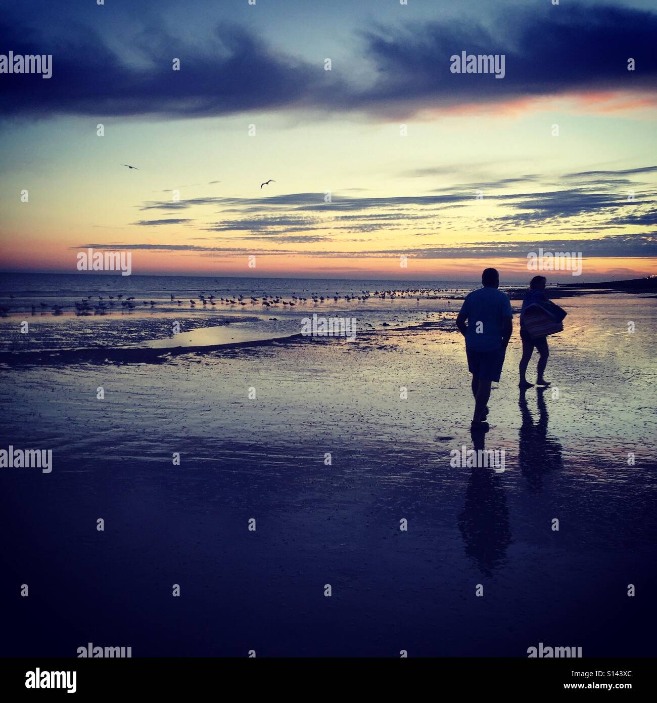 A couple walking on the beach at sunset Stock Photo - Alamy
