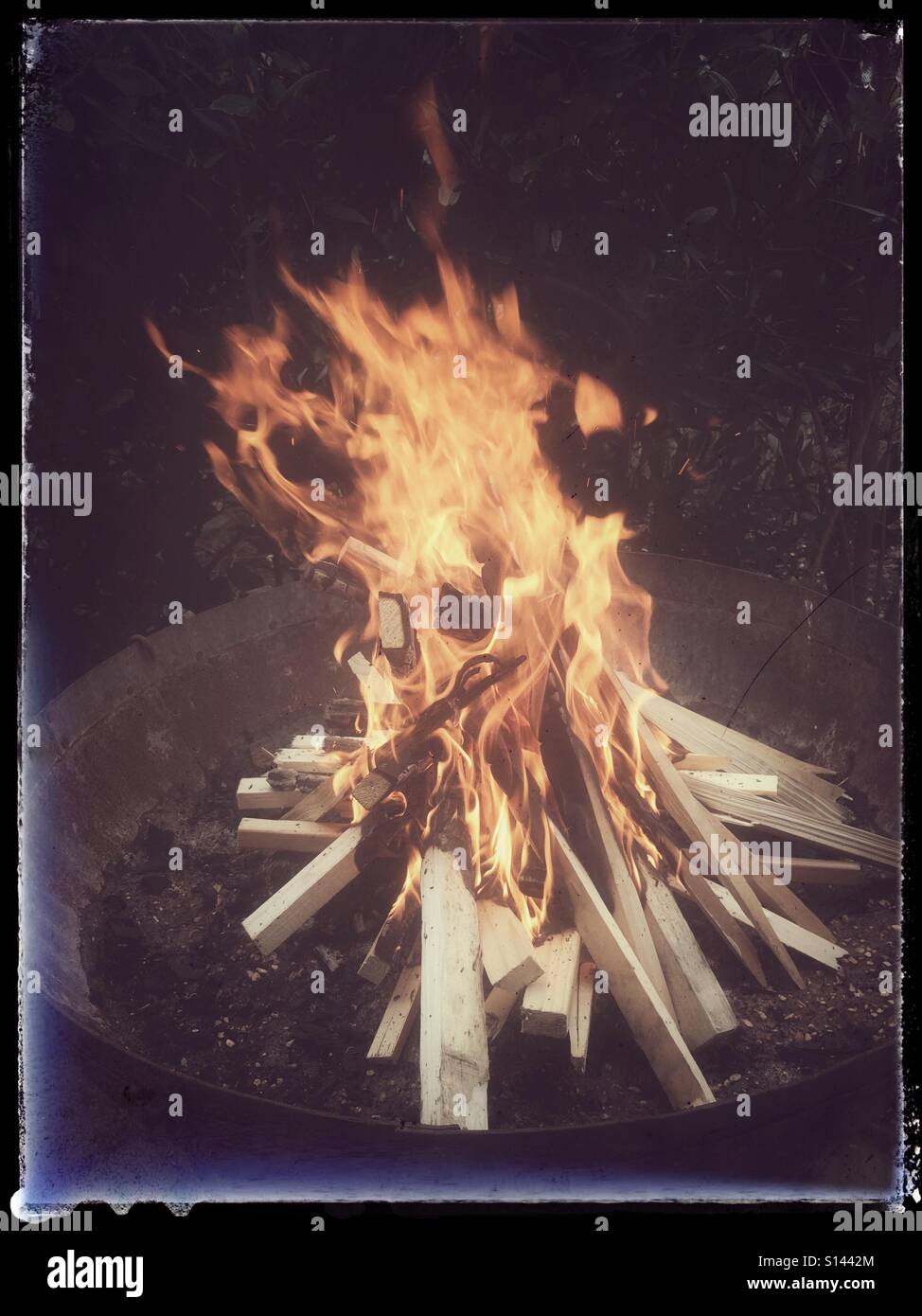 Firewood burning in firebowl outdoors - Smartphone Captured Stock Image