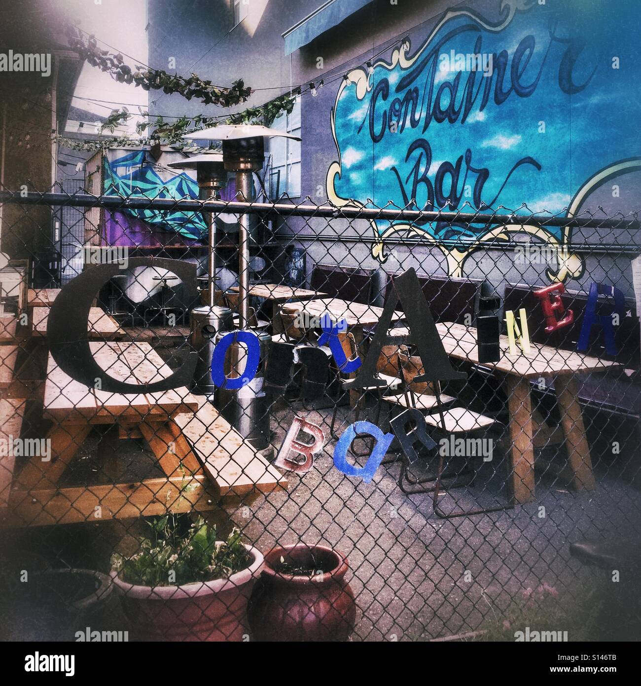 A shipping container nestled between buildings serves as an open-air pub. - Smartphone Captured Stock Image