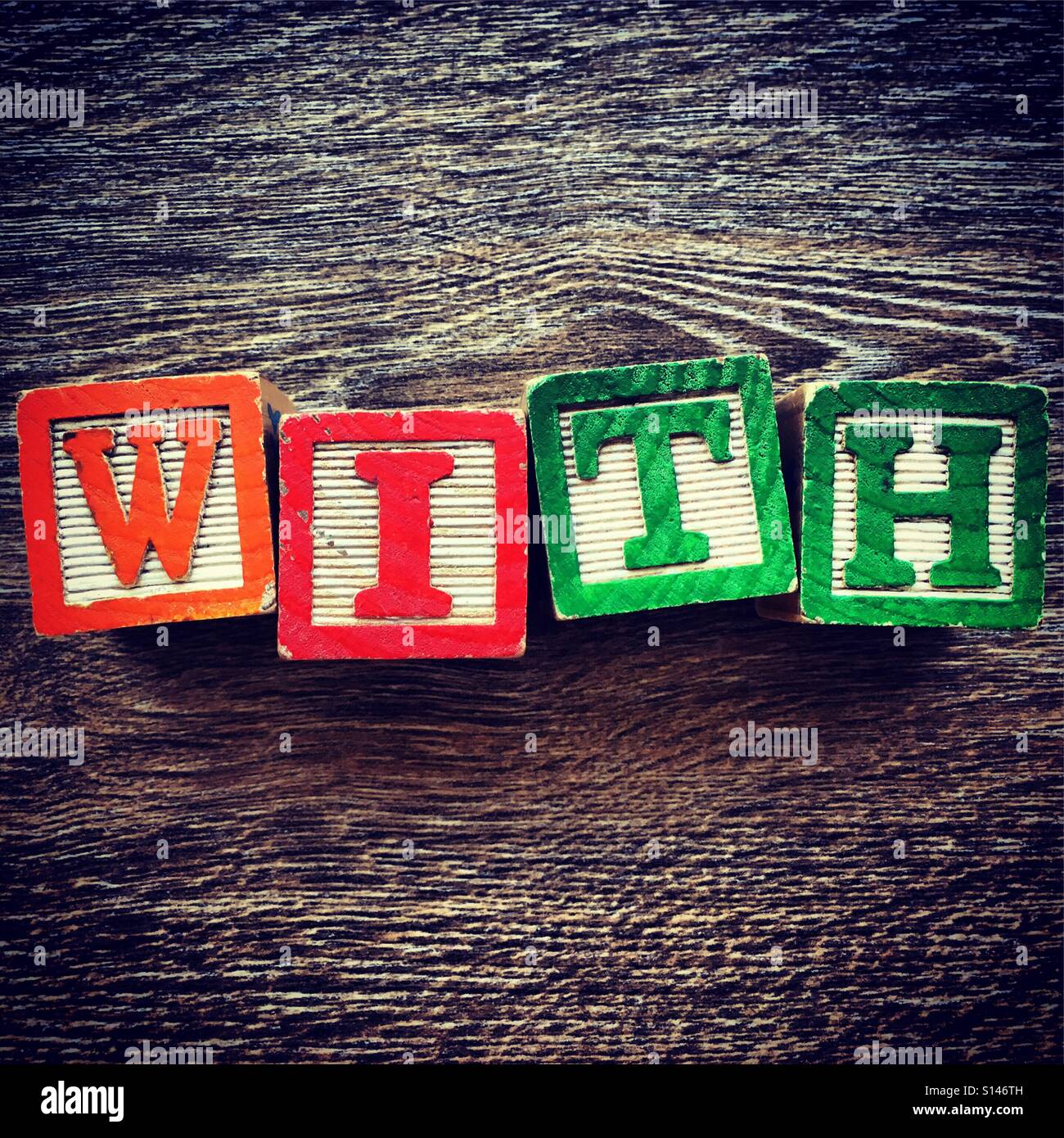 WITH word written with wood block characters - Smartphone Captured Stock Image