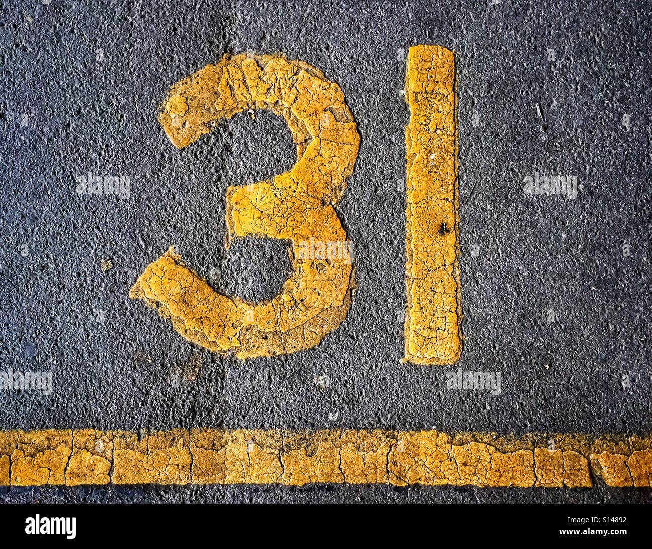 The yellow number 31. A car parking space identified by it's number and underlined by a solid yellow line. Photo Credit - © COLIN HOSKINS. - Smartphone Captured Stock Image