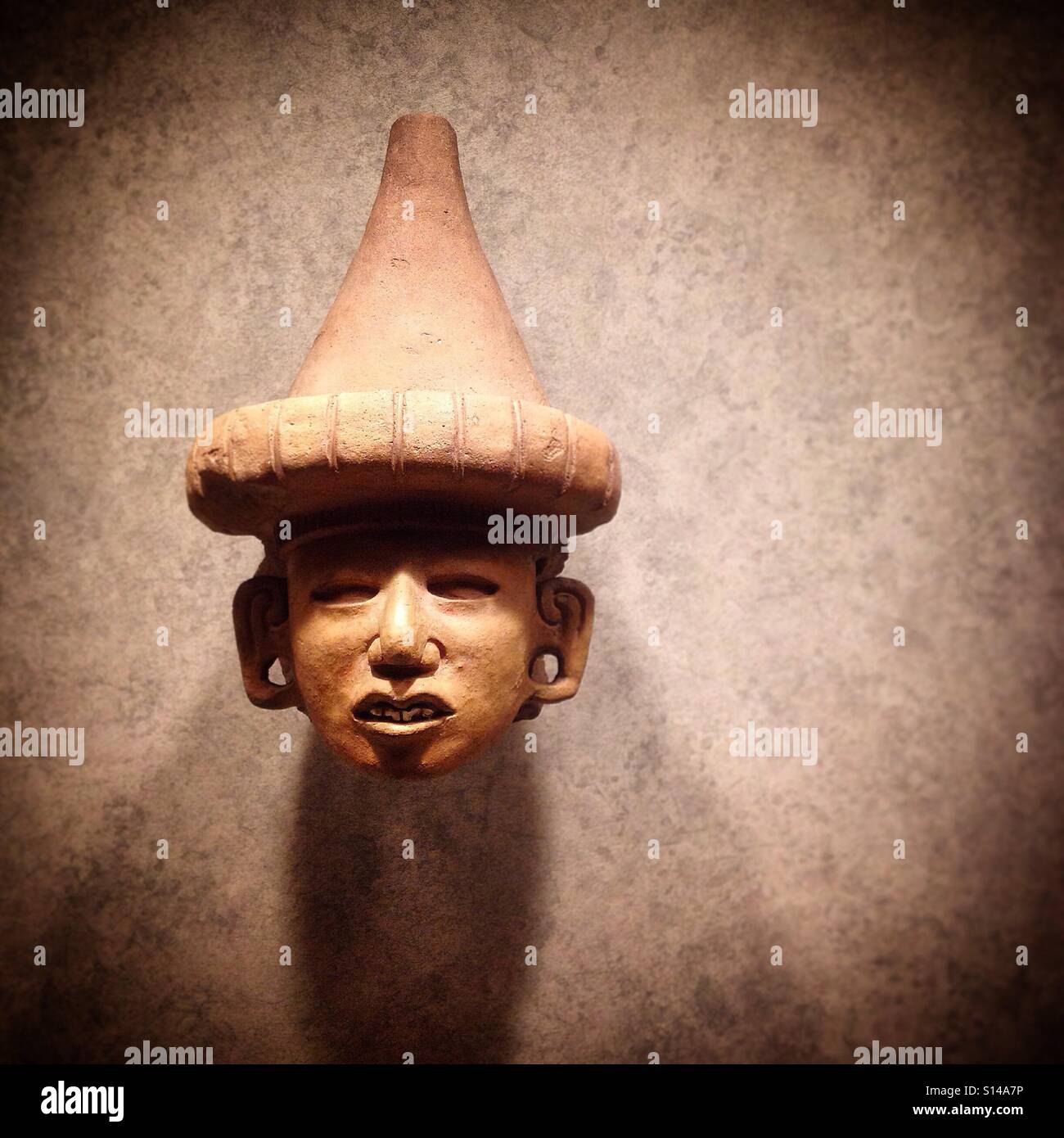 A head of a Mesoamerican Pre-Hispanic indigenous wearing a pointed hat decorates the Museo Nacional de Antropologia in Mexico City, Mexico - Smartphone Captured Stock Image