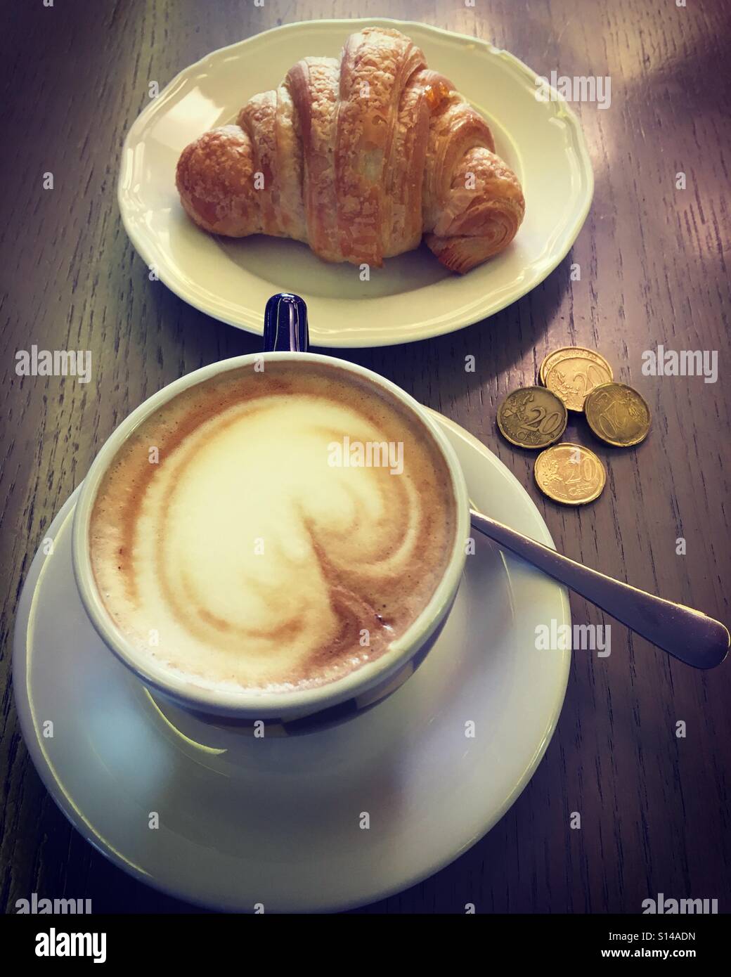 Italian breakfast with croissant and cappuccino and euro coins Stock Photo