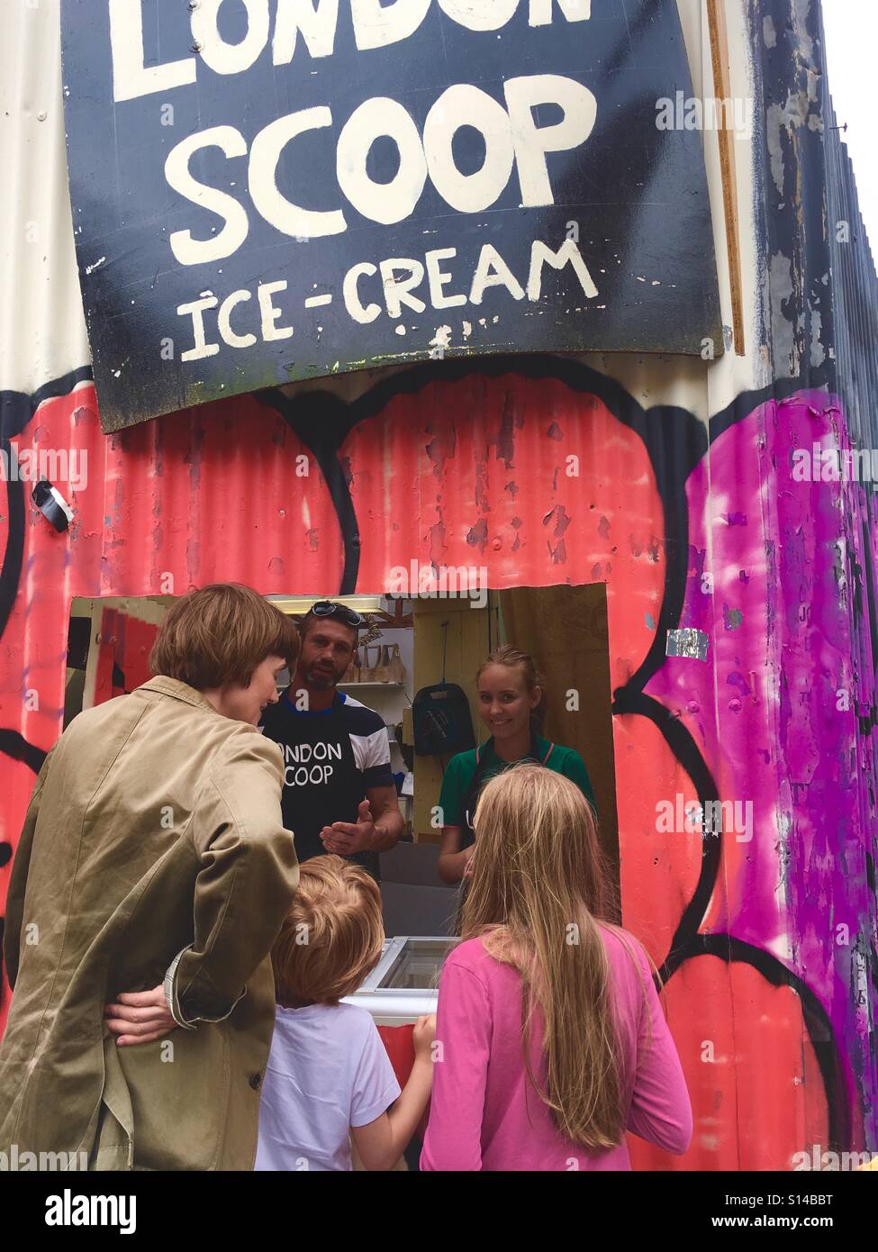 Mother and 2 children ordering ice cream in front of an unusual ice