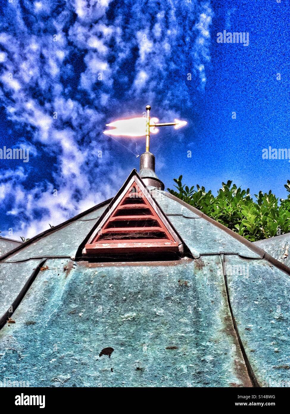Weather vane against blue sky with golden glow - Smartphone Captured Stock Image