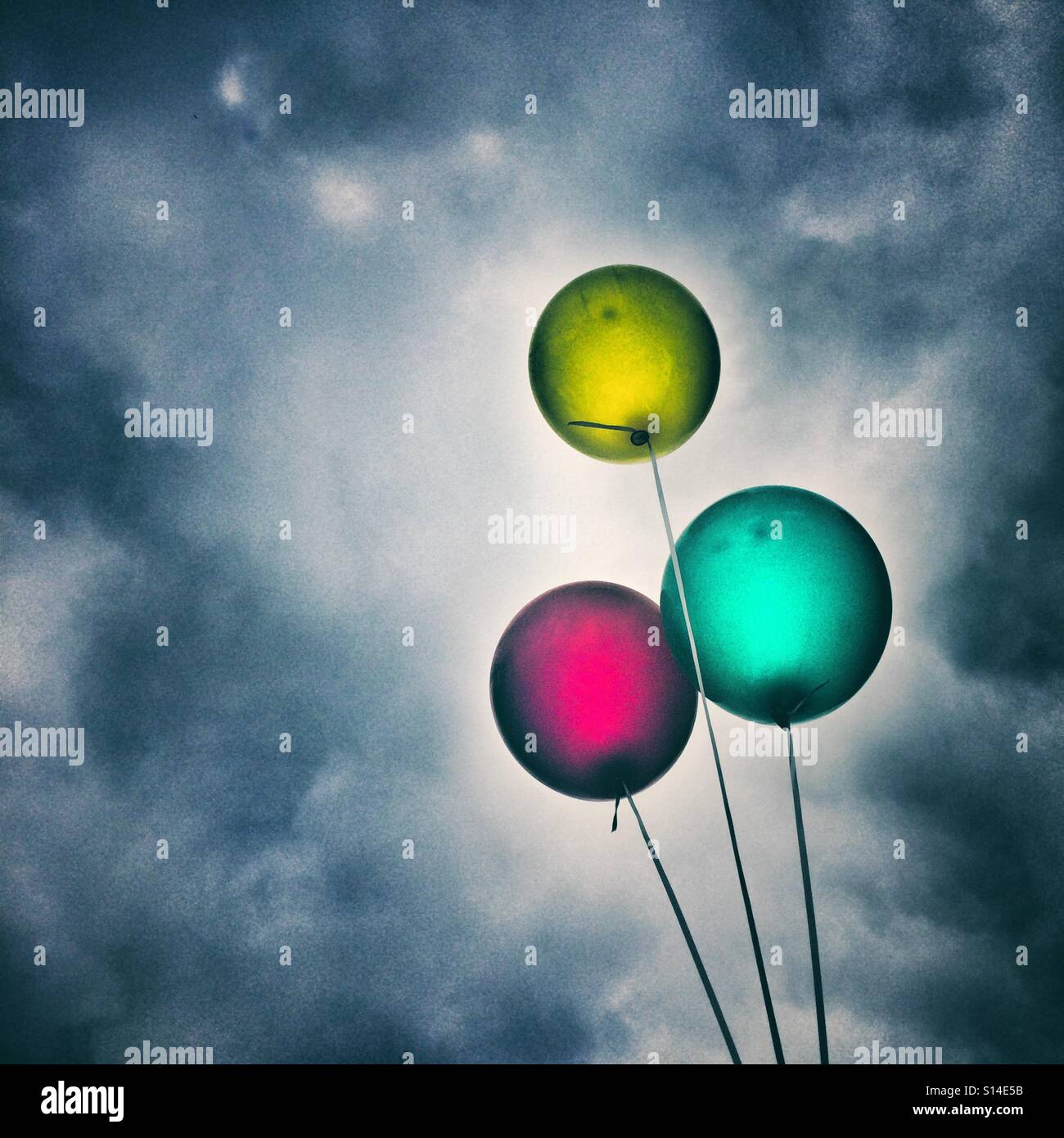 Three balloons against a dark cloudy sky Stock Photo