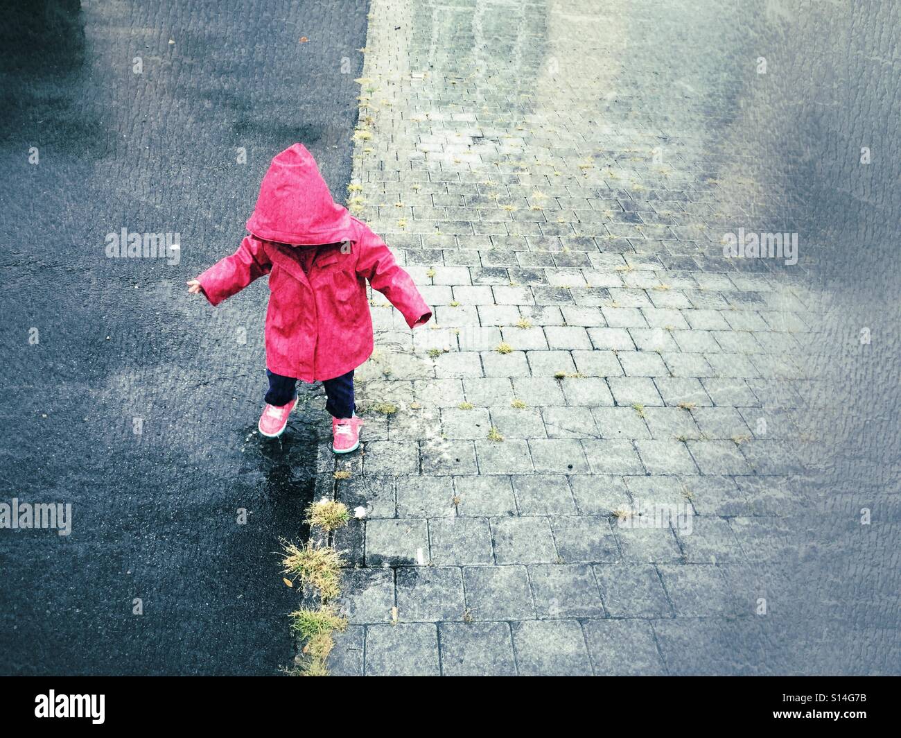 Toddler playing outside in rainy day - Smartphone Captured Stock Image