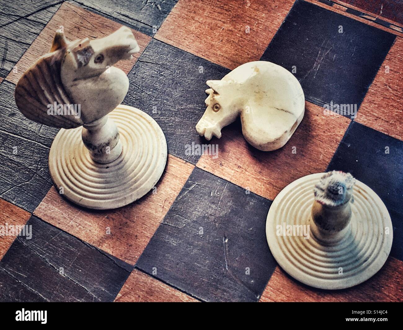 Two Knights on an antique chess board, one knight is broken. - Smartphone Captured Stock Image