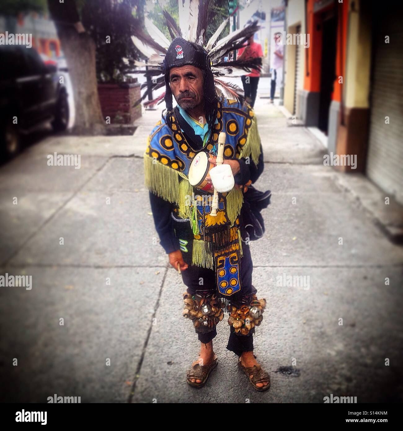 A Mexican dressed as an Aztec dancer plays music in the street in Colonia Roma, Mexico City, Mexico Stock Photo