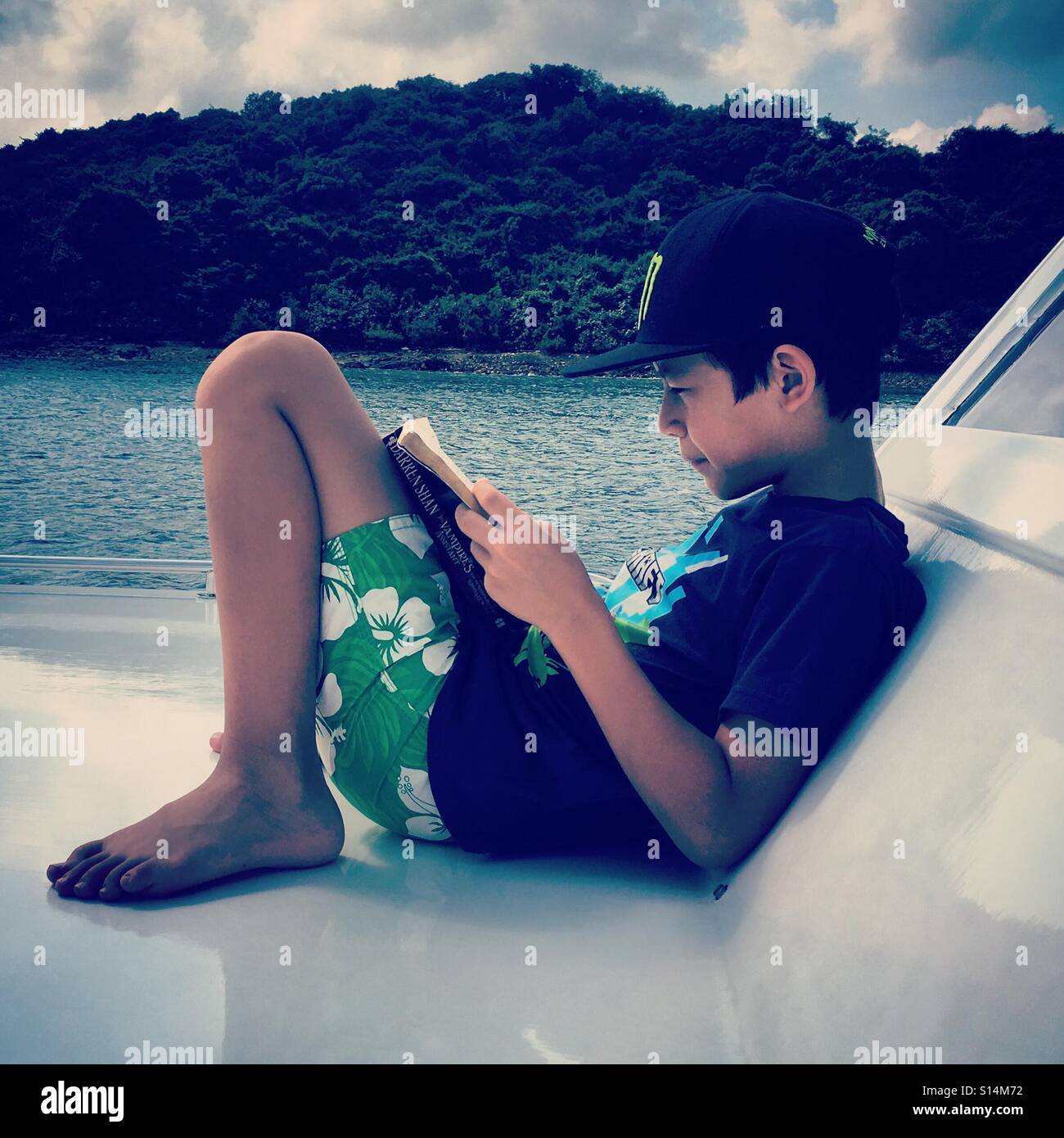Reading boy on a boat - Smartphone Captured Stock Image