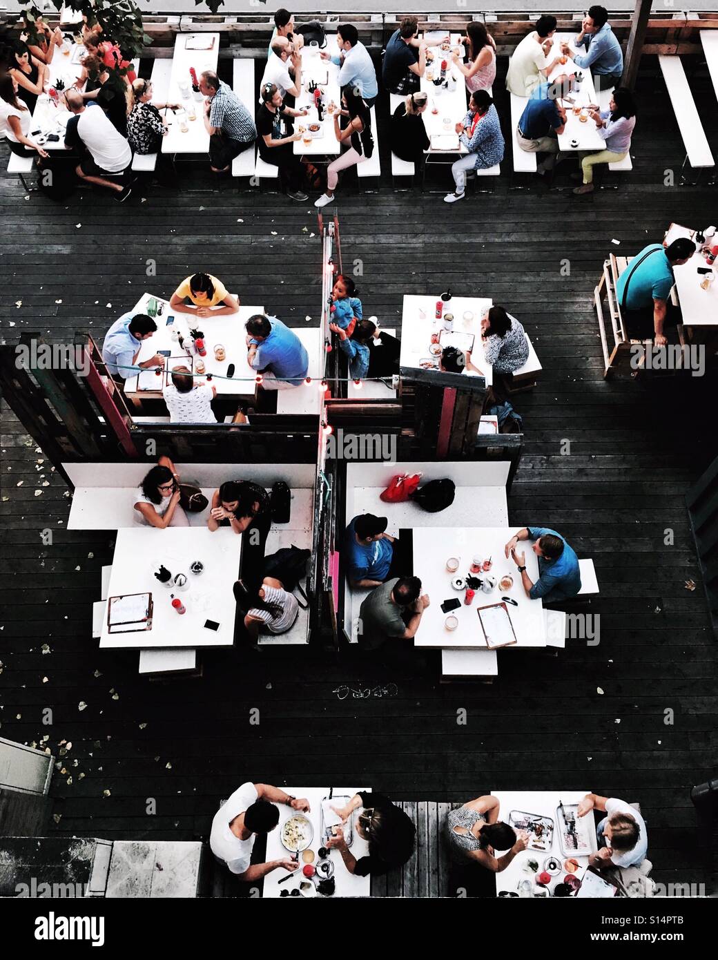 Photo taken from above of people eating outside at white tables. Stock Photo