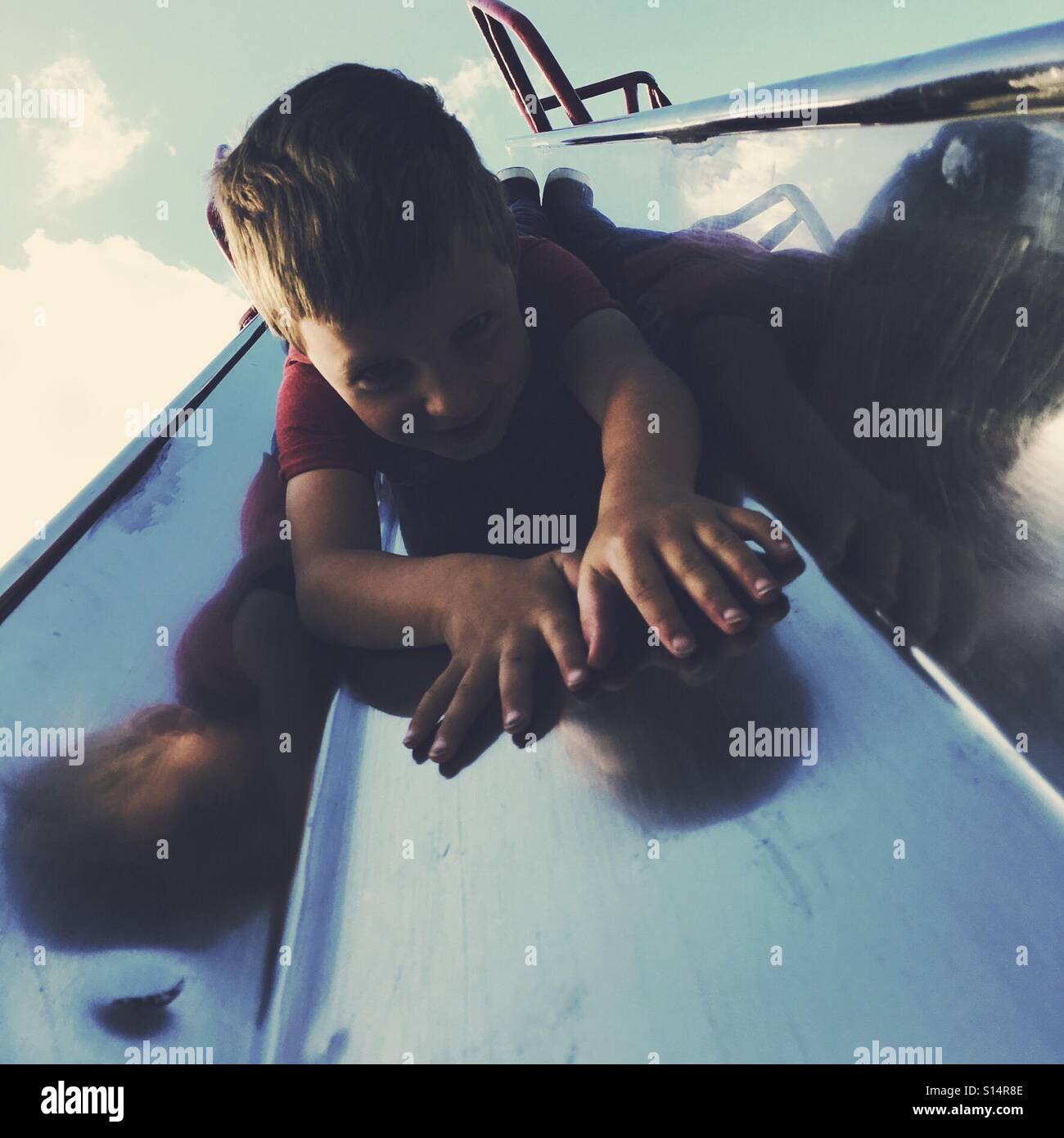 Young boy come down a slide head first Stock Photo