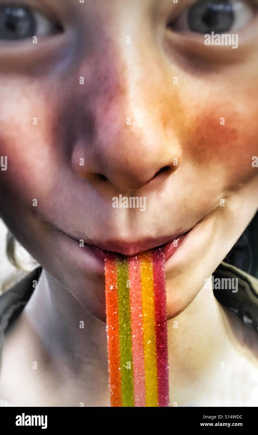 Young girl sucking on rainbow ribbon sweet Stock Photo