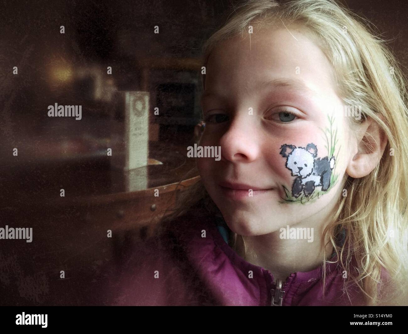 A girl has a panda bear painted on her cheek. Stock Photo