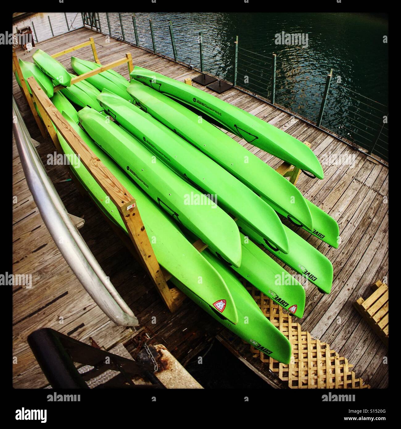 Neon green kayaks stacked on a dock. They look like a bunch of green bananas. Stock Photo