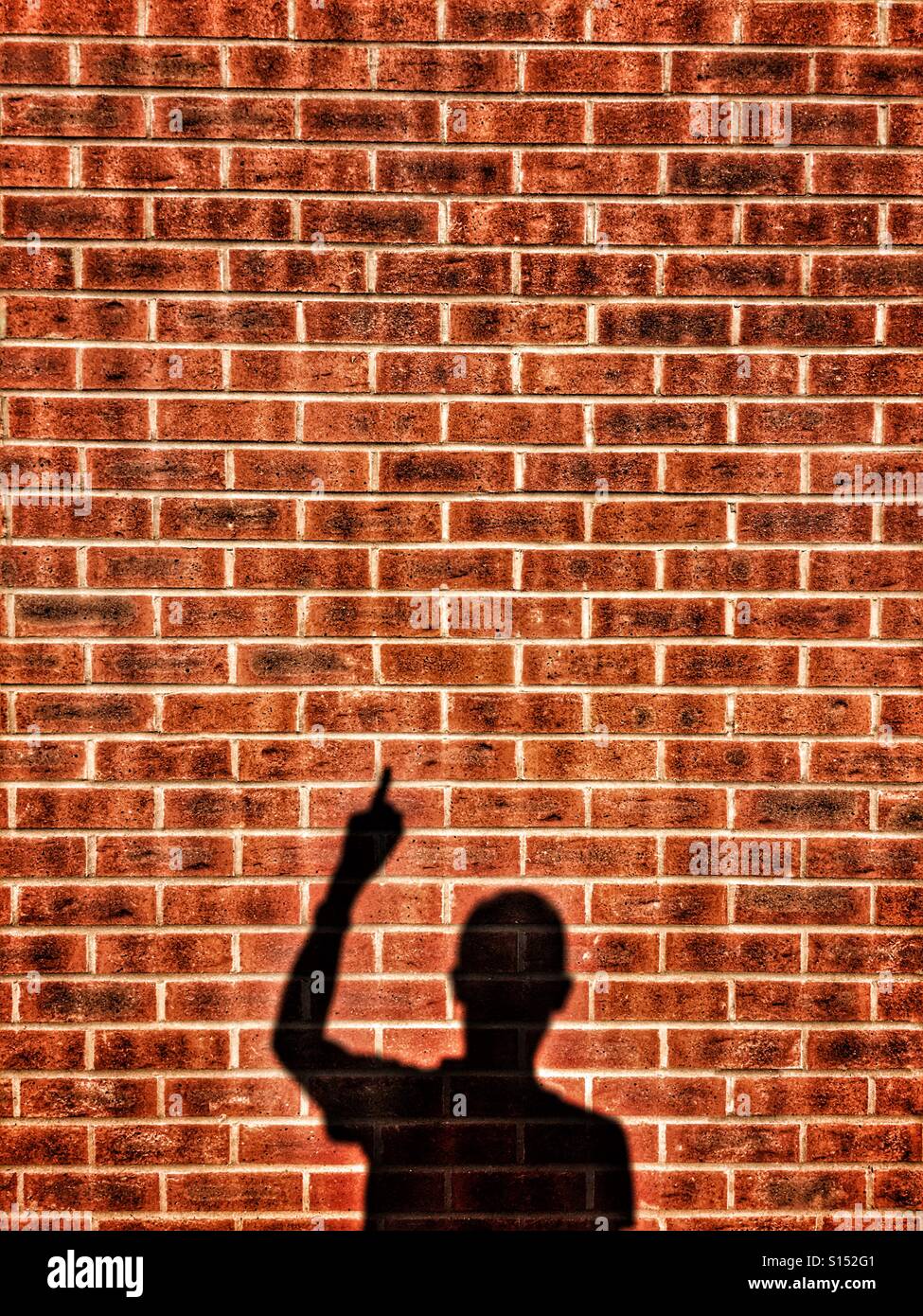 Shadow of man pointing on a brick wall Stock Photo