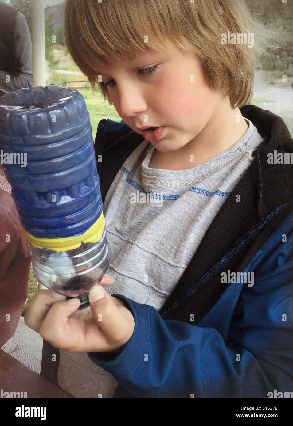 A boy paints a bottle as part of a camp project. - Smartphone Captured Stock Image